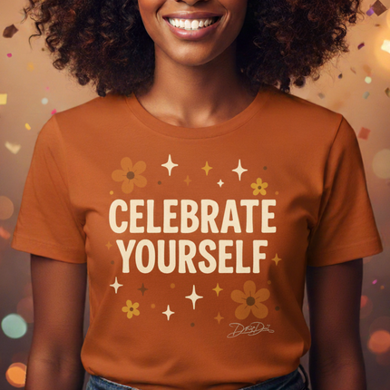 Woman wearing a 'Celebrate Yourself' t-shirt against a festive background with colorful lights.