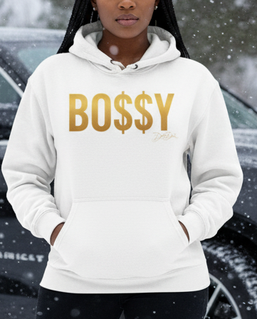 Person wearing a hoodie with 'BOSSY' text in front of a black SUV in a snowy setting