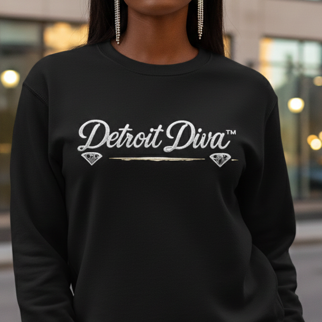 Woman wearing a black sweatshirt with 'Detroit Diva' text, standing in an urban setting.