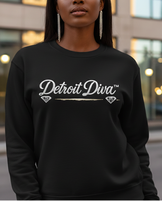 Woman wearing a black sweatshirt with 'Detroit Diva' text, standing in an urban setting.
