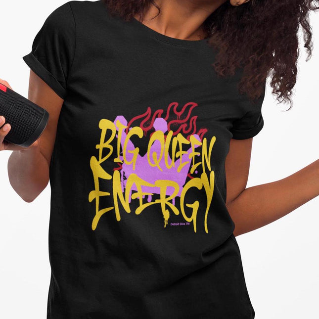 Person wearing a black t-shirt with colorful text design that says Big Queen Energy on a white background