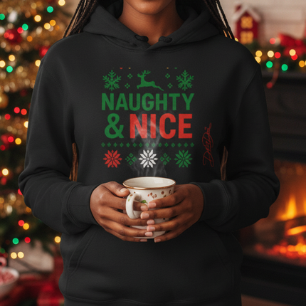 Woman wearing a 'Naughty & Nice' hoodie holding a mug in a festive room with Christmas decorations.