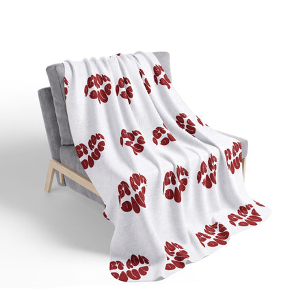 White blanket with red lip  patterns draped over a gray chair on a white background